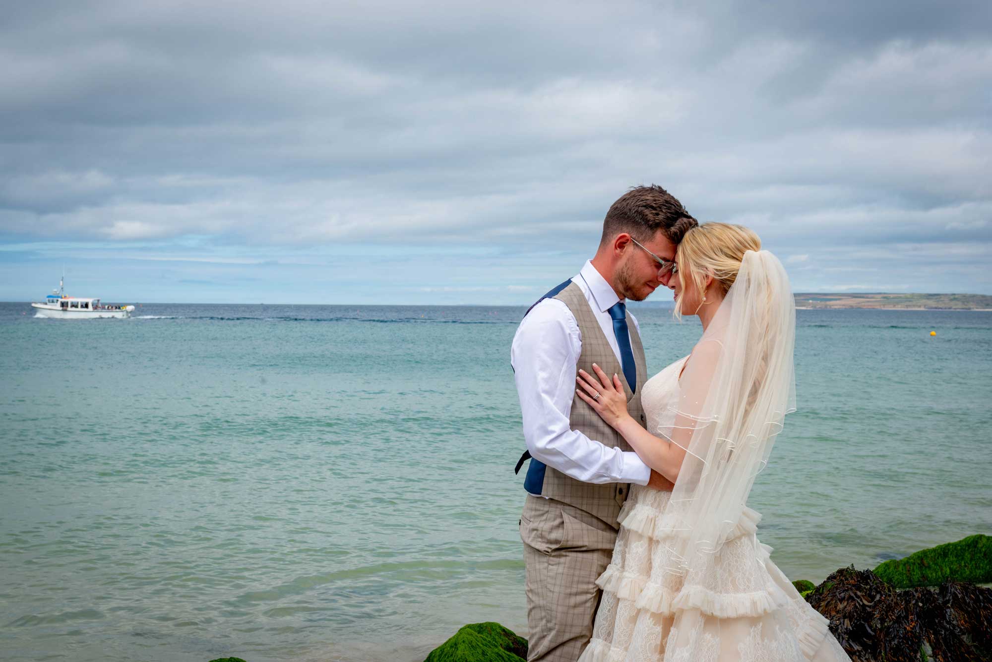 Bride and groom embracing with Cornish sea backdrop at St Ives Harbour Hotel